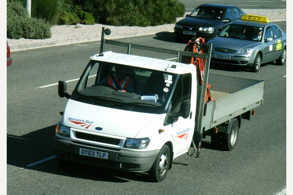 Carrinha Ford Transit branca de caixa aberta com taipais