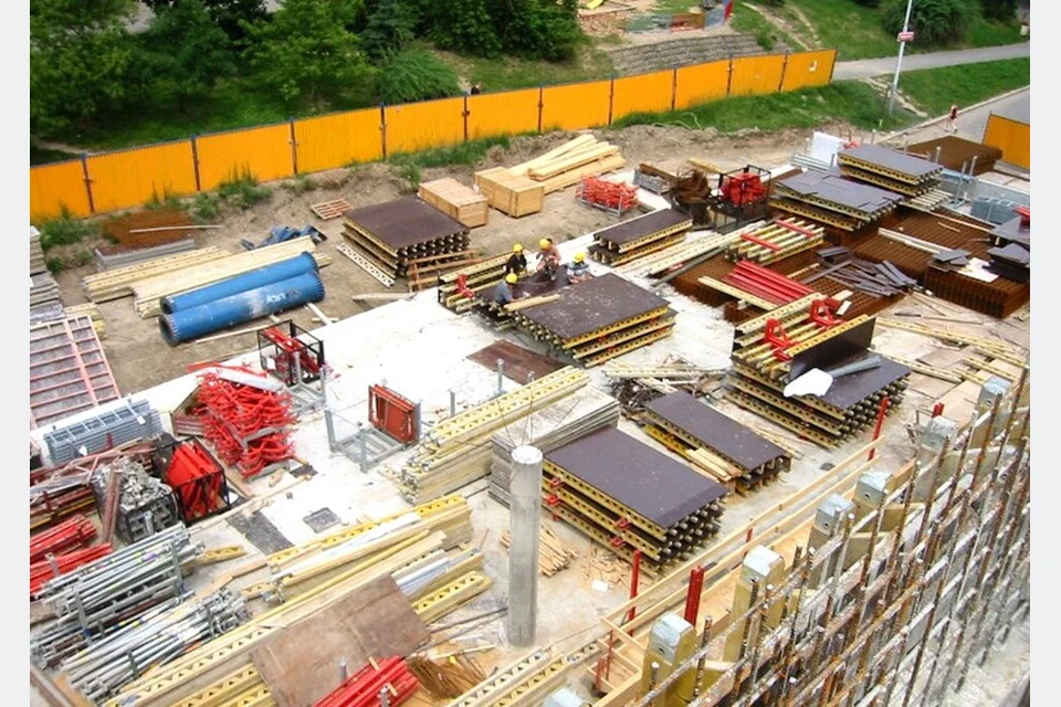 Painéis modulares de cofragem e componentes organizados num estaleiro.