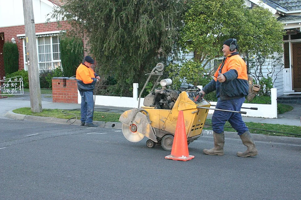 Cortadora de juntas de condução a pé a cortar um pavimento.